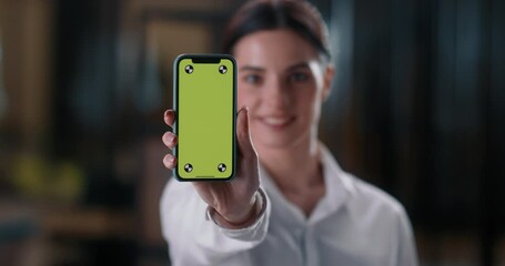 Woman looks screen smartphone and stretches hand with smartphone display game. Close-up green chroma key on smartphone display insert advertisement for your product service application. 