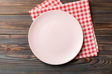 Wall Mural - Top view on colored background empty round pink plate on tablecloth for food. Empty dish on napkin with space for your design