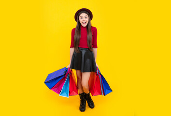 Poster - Happy teenager portrait. Funny teen girl hold shopping bag enjoying sale isolated on yellow. Portrait of teenager schoolgirl is ready to go shopping. Smiling girl.