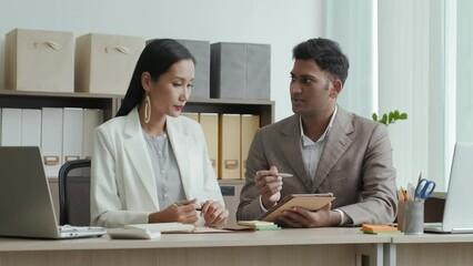 Wall Mural - indian businessman discussing something on digital tablet with asian female colleague during office 