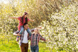 © Angelov - Outdoor portrait of happy young family playing in spring park under blooming tree, lovely couple with little child having fun in sunny garden