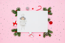 Christmas Card With Copy Space. Princess On Blank White Paper In Frame Of Natural Fir Tree Branches, Gifts And Decorations On Pastel Pink Flat Lay Background
