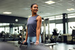 © Flamingo Images - Smiling woman lifting dumbbells at the gym