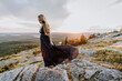 © Cavan Images - wind blows woman with long hair and dress at sunset on mountain