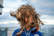 © Cavan Images - A young girl on ferry boat deck with wind blowing her hair
