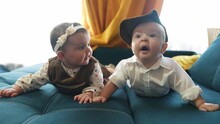 Twin Babies In Retro Clothes. Brother And Sister A Twins Kids Sit On The Couch Lifestyle In Retro Clothes Cap Play Among Themselves. Happy Family Kid Dream Twin Concept