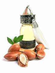 Wall Mural - Argan oil in a oriental glass and metal bottle and argan nuts with green leaves isolated on white background.