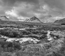 Wall Mural - Black and white Majestic Winter landscape image of River Etive in foreground with iconic snowcapped Stob Dearg Buachaille Etive Mor mountain in the background