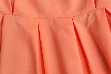 Wall Mural - Part of skirt or dress is pale pink shade close-up. Peach clothing in fold of bright color, texture background