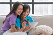 © kaew6566 - Cheerful lgbt asian couple looking tablet shopping online app using credit card payment goods sitting together on sofa at home. Happy lesbian shopping delivery use credit card. Banking internet money.