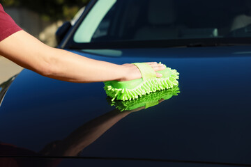 Man cleaning car hood outdoors, closeup view