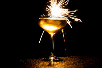 New Years Eve celebratory champagne glass with sparkler shining above it.