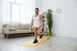 © SHOTPRIME STUDIO - Man sports home training on the floor on a mat with dumbbells, exercises for muscle growth, pumped up man fitness trainer exercises at home, the concept of health and beauty of the body