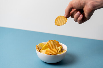 a simple concept of junk food, hand pick a single potato chip from bowl