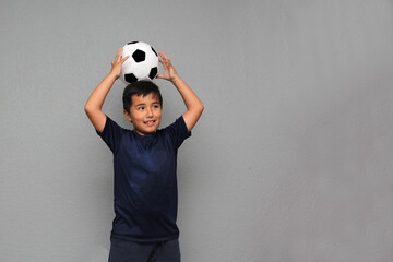 Hispanic Latino 8-year-old boy plays with a soccer ball very excited that he is going to see the football game and wants to see his team win