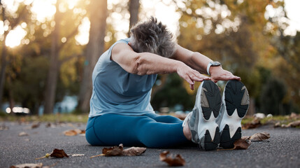 Canvas Print - Senior woman, stretching and exercise on asphalt road for fitness, workout and touching feet with lens flare and autumn leaves at nature park. Female on group for warm up and cardio training outdoor