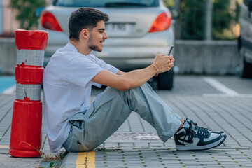 Canvas Print - teenager in the street sitting with mobile phone or smartphone