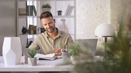 Poster - Happy businessman in casual using laptop in home office, Young adult man sitting at desk in study room, working online with computer, browsing the Internet, smiling.