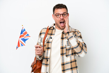 Wall Mural - Young hispanic man holding an United Kingdom flag isolated on white background with surprise and shocked facial expression