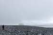 Hiker at the rocky and foggy shore in Antarctica