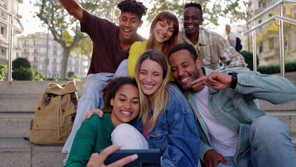 Wall Mural - Happy young group of diverse people having fun taking selfie portrait while sitting together outdoors during travel holidays. Multiracial friendship and vacation concept