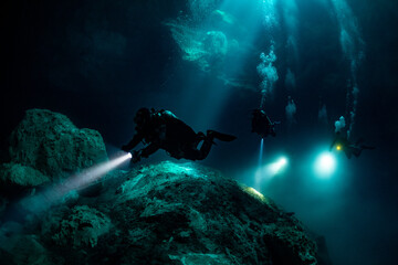 Canvas Print - cave diver instructor leading a group of divers in a mexican cenote underwater