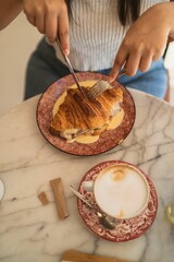 Poster - Vertical closeup of a table with a croissant sandwich and a cappuccino