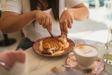 Poster - Closeup of a table with a croissant sandwich and a cappuccino