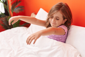 Adorable hispanic girl somnambulist sleepwalking sitting on bed at bedroom