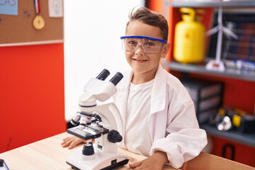 Poster - Adorable hispanic toddler student using microscope standing at classroom