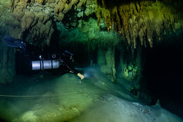 Wall Mural - cave diver instructor leading a group of divers in a mexican cenote underwater