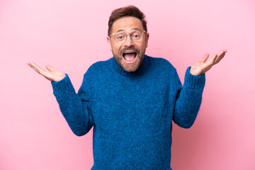 Middle age caucasian man isolated on pink background with shocked facial expression