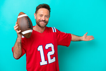 Wall Mural - Middle age caucasian man playing rugby isolated on blue background extending hands to the side for inviting to come