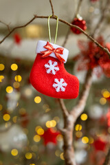 Re felt boot Christmas decoration hanging on twigs with gold light bokeh and blurry background