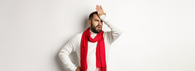 Annoyed man slap his forehead and cursing, forgetting buy christmas gifts, facepalm and standing bothered against white background