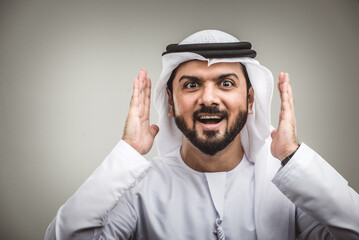 Wall Mural - Handsome arab man wearing traditional emirate clothing portrait in studio - Middle eastern businessman isolated on cut-out gray background