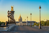 Fototapeta Paryż - Dome of Les Invalides seen across Pont Alexandre III bridge at sunrise in Paris. France