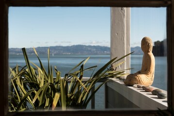 Sticker - Old stone buddha statue outside of a beachfront balcony in Tiburon, California