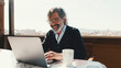 © Andrii Nekrasov - Happy middle aged man communicates remotely using laptop. Working from home office