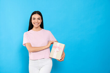 Canvas Print - Happy young woman holding gift box on light blue background