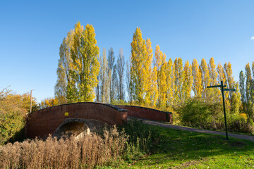 Wall Mural - Old red brick bridge at the canal in autumn season. Grand Canal in Milton Keynes. England