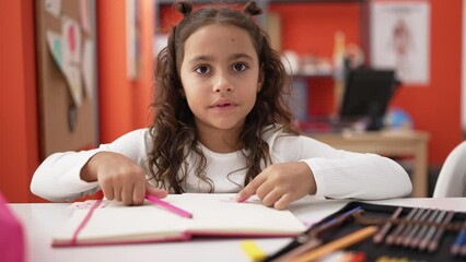 Poster - Adorable hispanic girl student sitting on table drawing on notebook at classroom