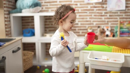 Wall Mural - Adorable caucasian girl playing with play kitchen standing at kindergarten