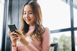 © sorapop - Happy beautiful female typing text message on smart phone device and enjoyment lifestyle with social networking media, Asian young woman using mobile phone at cafe coffee shop to shopping online