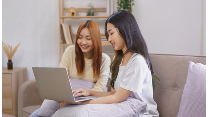 Wall Mural - Activity at home concept, LGBT lesbian couple read and typing data on laptop while working together