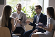 Four millennial professional teammates solve business gathered in briefing, informal meeting smile satisfied with work result, discuss collaborative task or project, share startup ideas. Seminar event