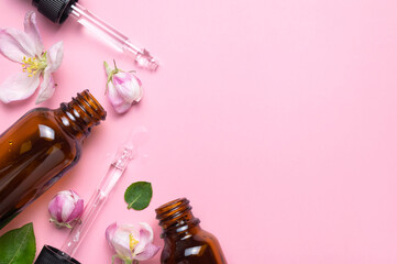 Wall Mural - Spring concept of natural organic cosmetics, beauty herbal product spa aroma oil. Mockup. Clean brown glass cosmetic bottles with dropper, delicate spring flowers on pink background flat lay top view