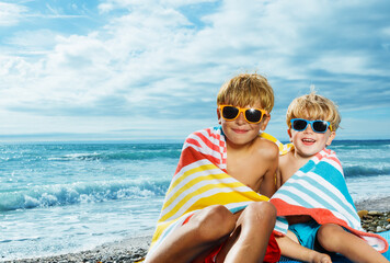 Wall Mural - Portrait of two little boys covered in beach towel over sea