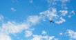The passenger airplane is flying far away in the blue sky and white clouds. Aircraft in the air. International passenger air transportation. Horizontal stories