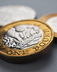 British coins lie on gray surface. One pound sterling coin closeup. Economy and money. Bank of England. UK currency and treasury. Pound vertical stories. Macro